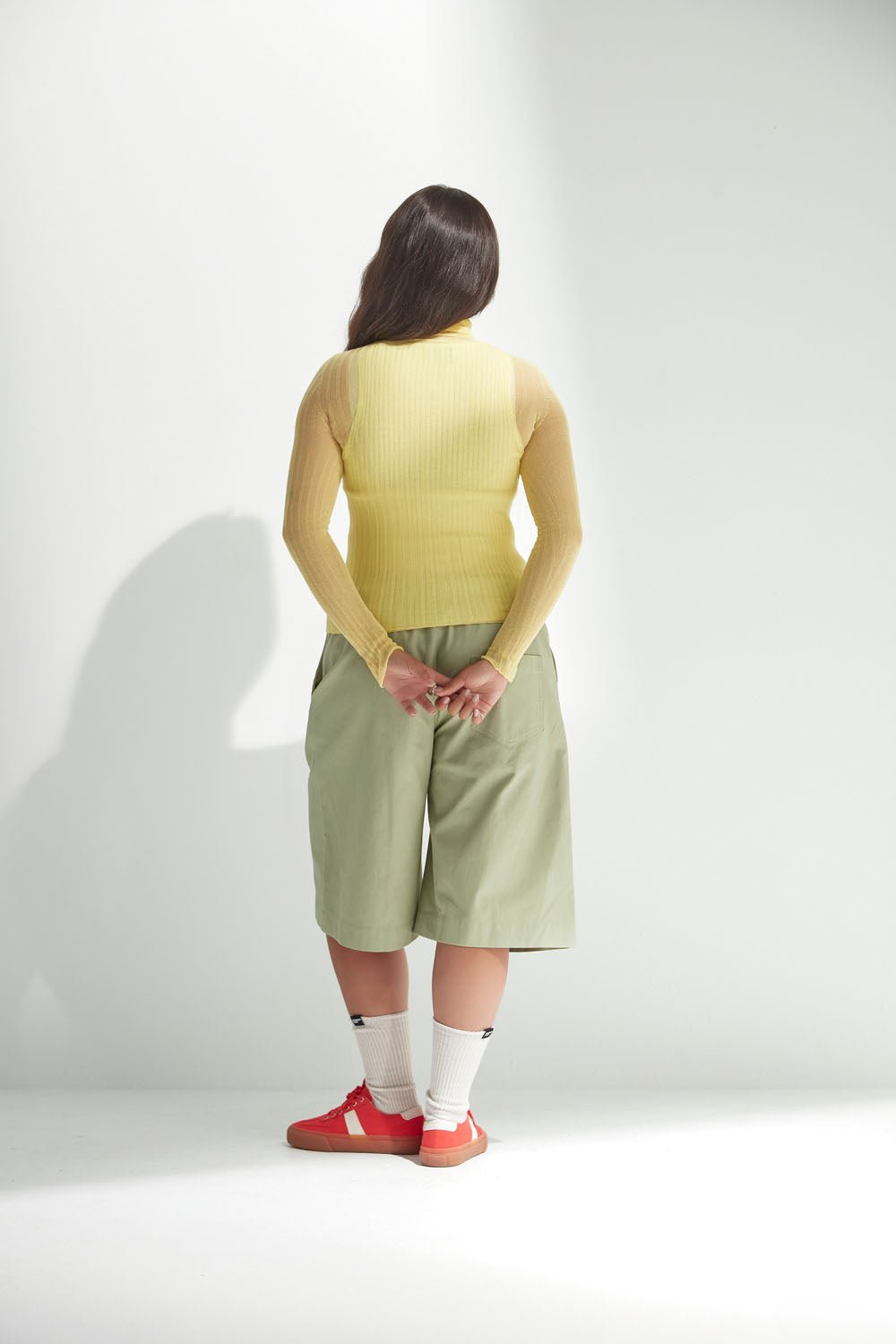 Person wearing a yellow tulle top and green shorts on a white background