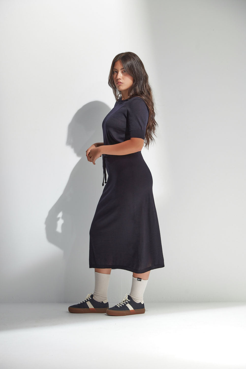 Woman wearing a navy dress standing against a white background