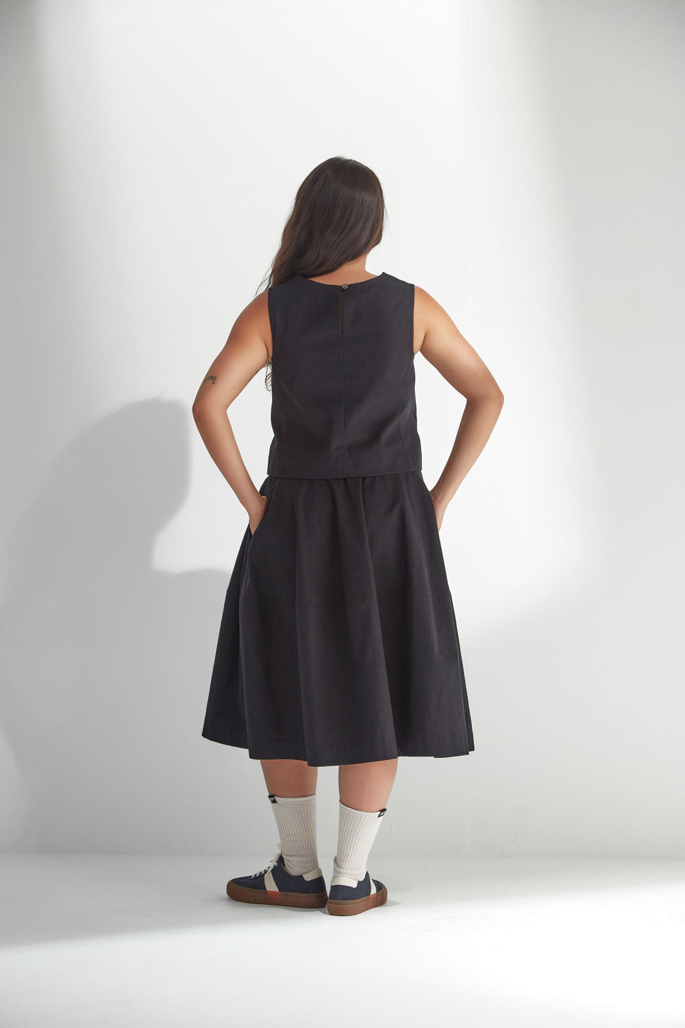 Woman wearing a black sleeveless top and skirt against a white background