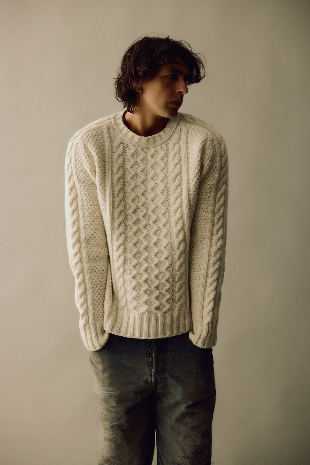 Person wearing a cream knitted sweater against a plain background