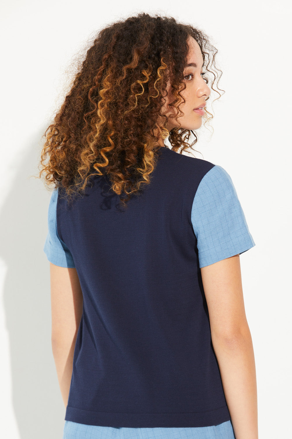 A woman looking over shoulder wearing a denim-coloured Standard Issue Grid Linen Tee.