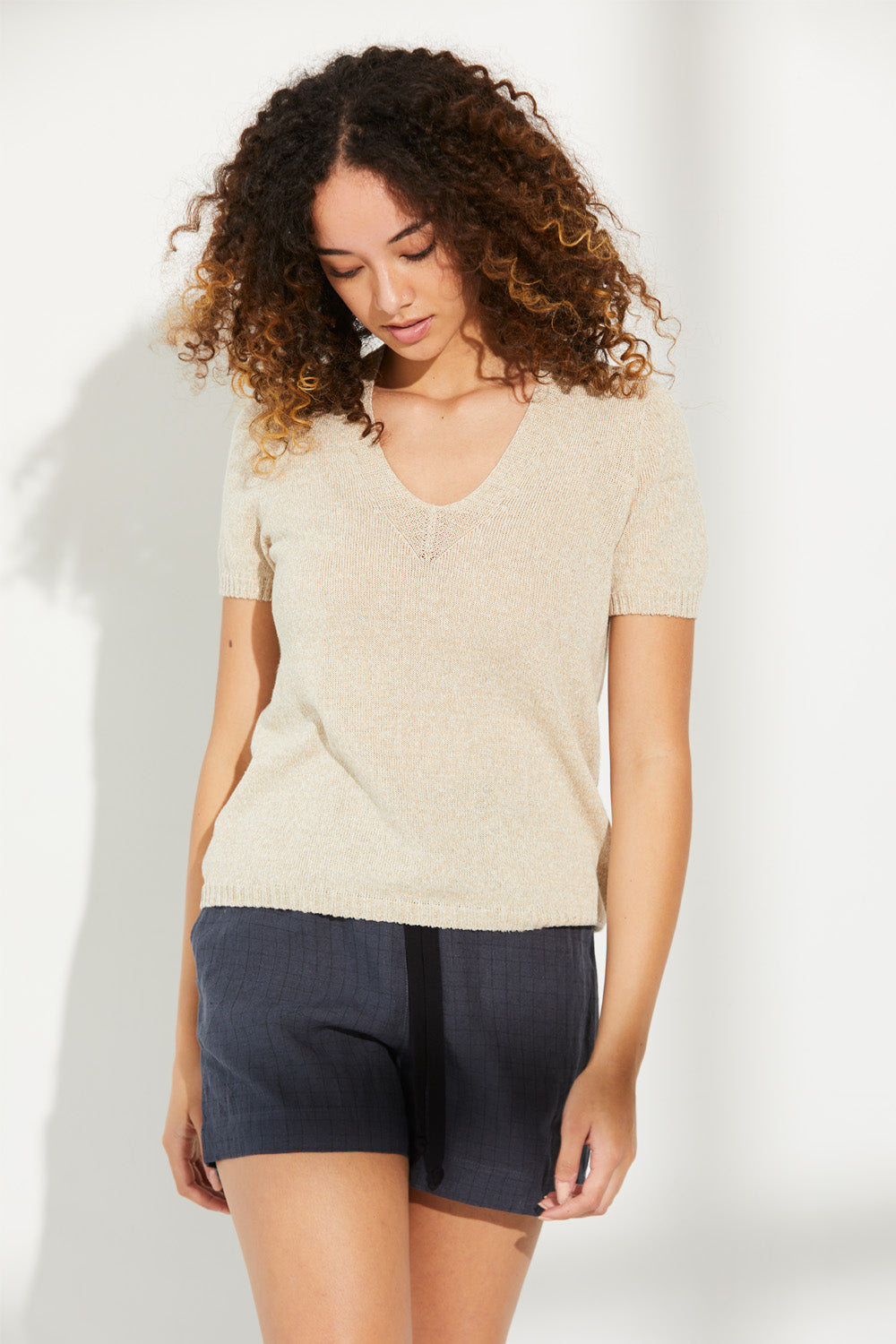 A woman standing wearing a grain-coloured Standard Issue Linen Tee.