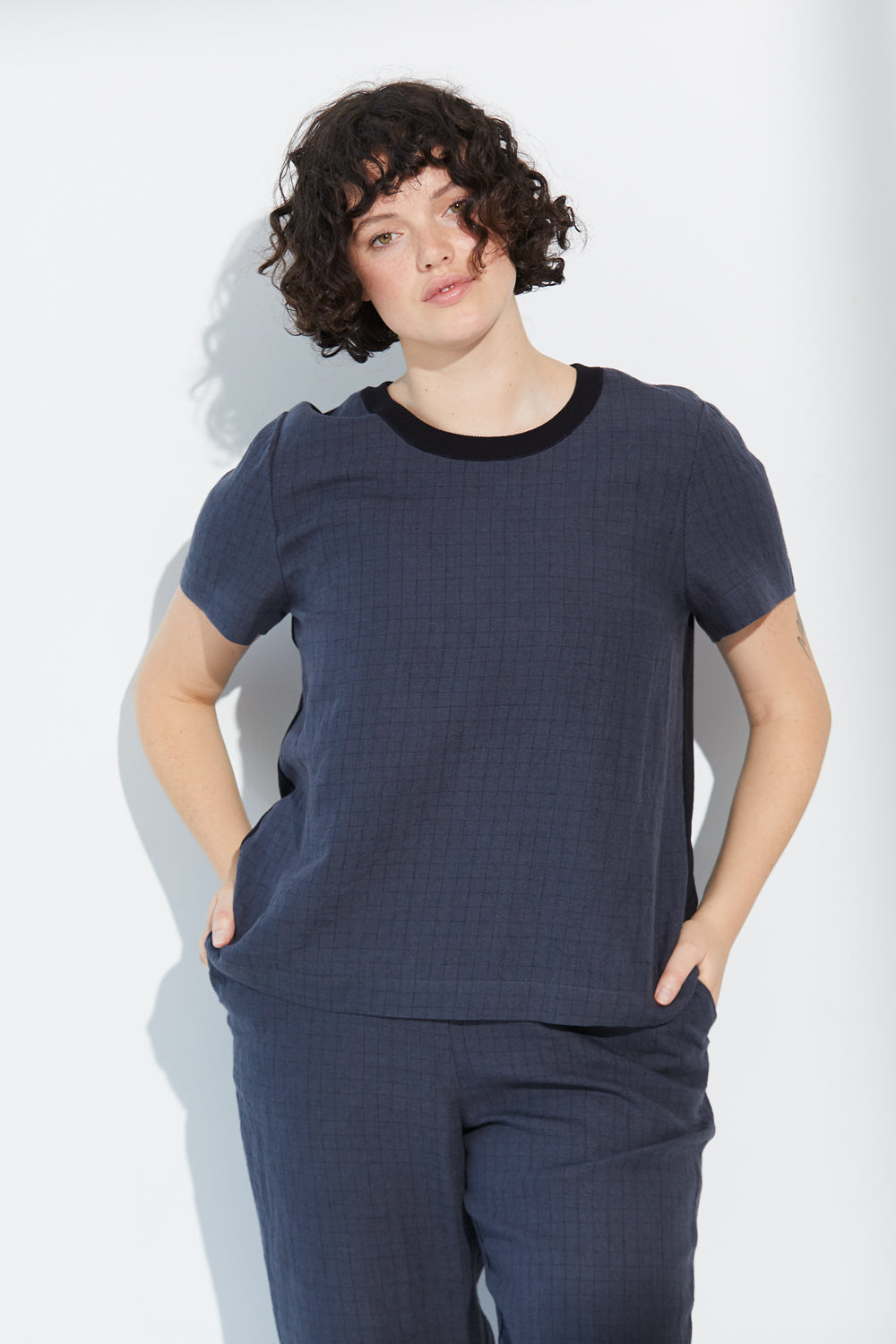 A woman standing wearing a charcoal-coloured Standard Issue Grid Linen Tee.