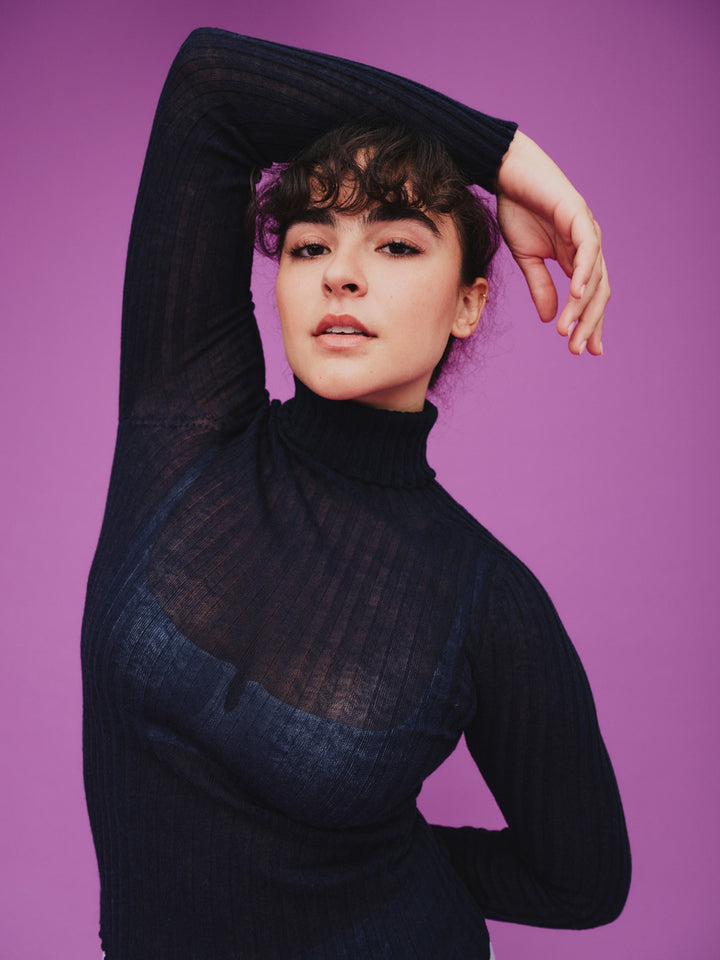Woman wearing a sheer navy tulle against a purple background