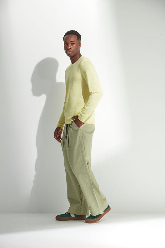 Man wearing a light yellow sweater and light green pants against a white background