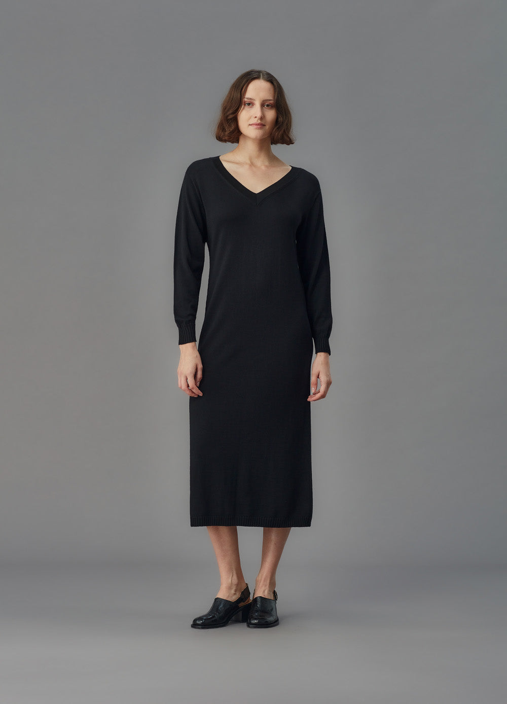 Woman wearing a black dress against a gray background
