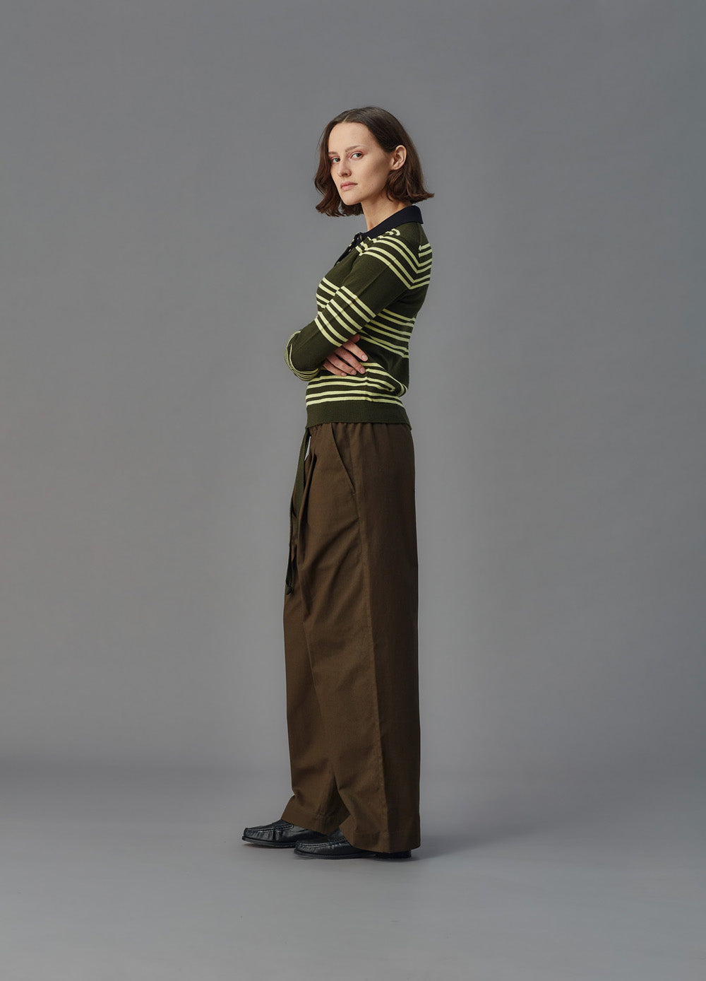 Person wearing a brown and yellow striped sweater with wide-leg brown pants on a gray background