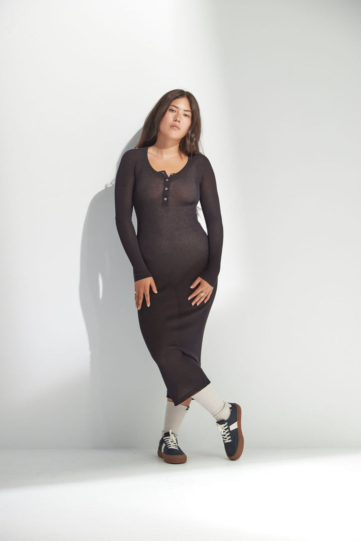 Woman wearing a long-sleeve black dress against a white background