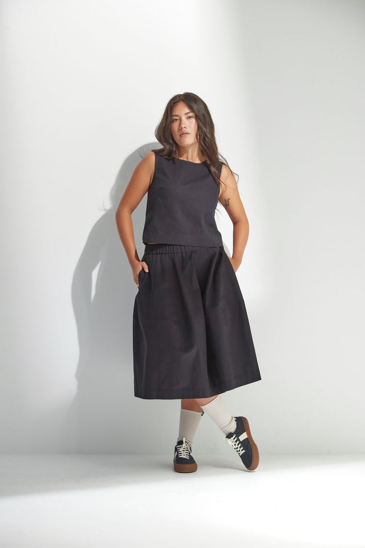 Woman wearing a black sleeveless top and skirt against a white background