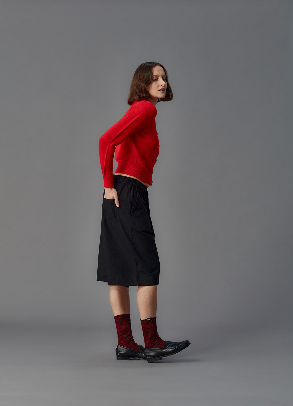 Person wearing a red sweater and black shorts on a gray background