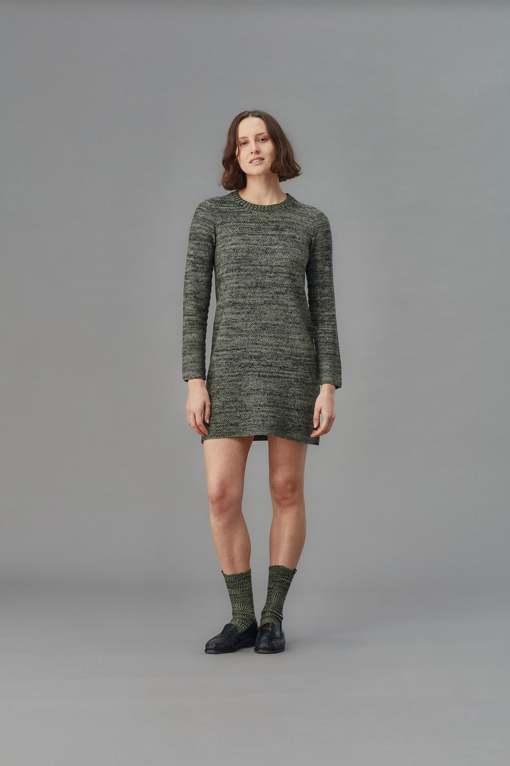 Woman wearing a green knitted dress on a gray background