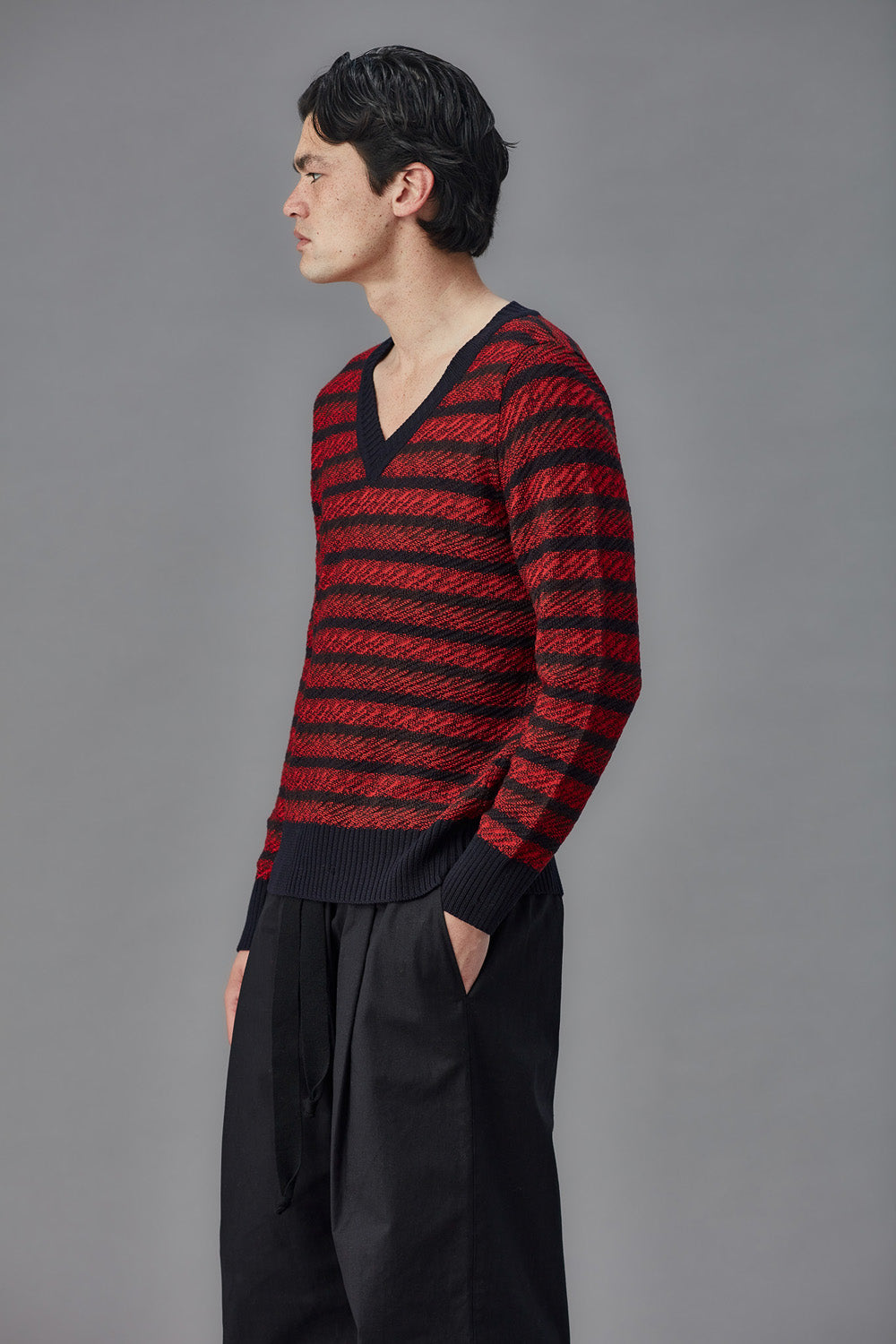 Man wearing a red and black striped sweater against a gray background