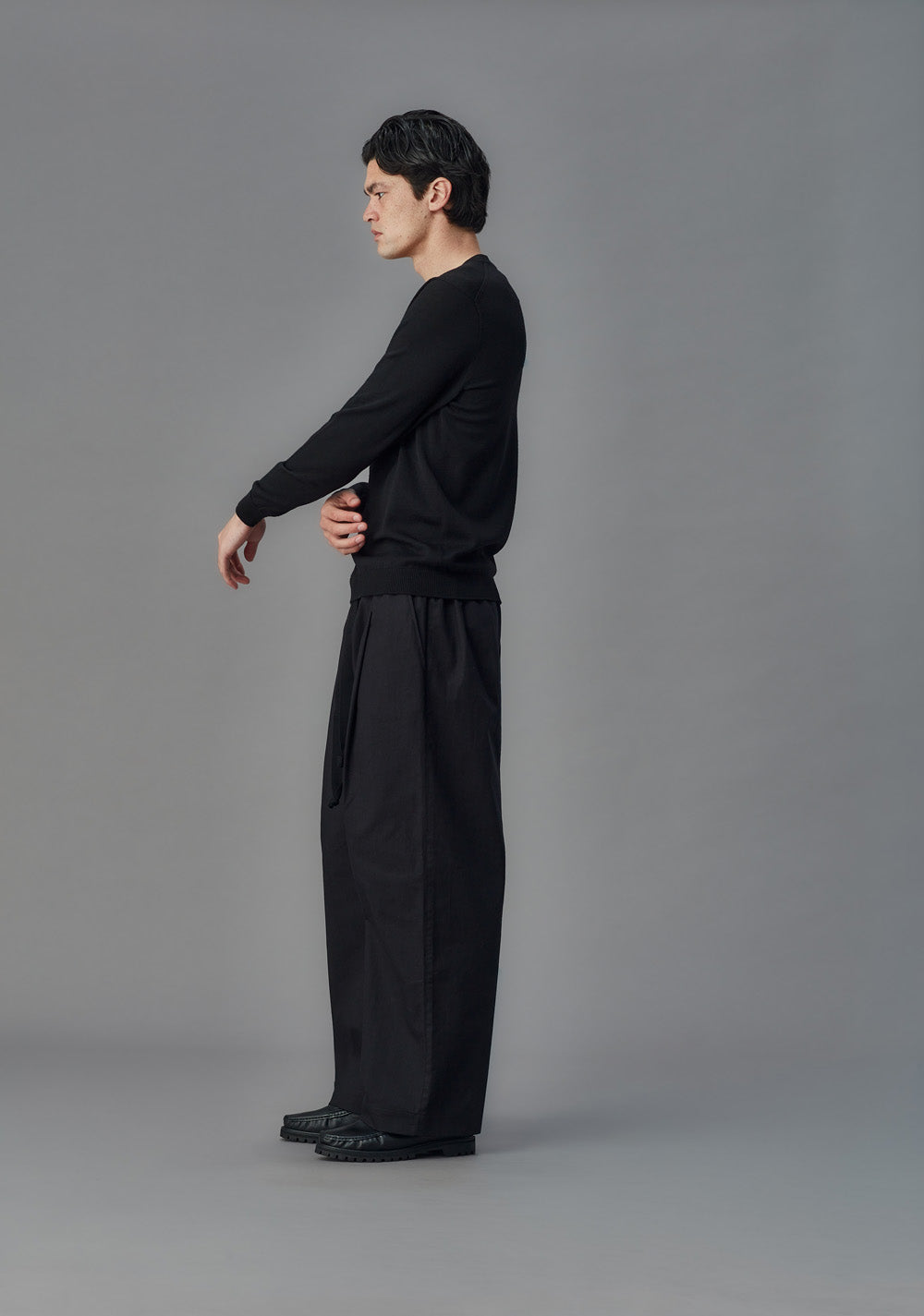 Person wearing a black outfit on a gray background