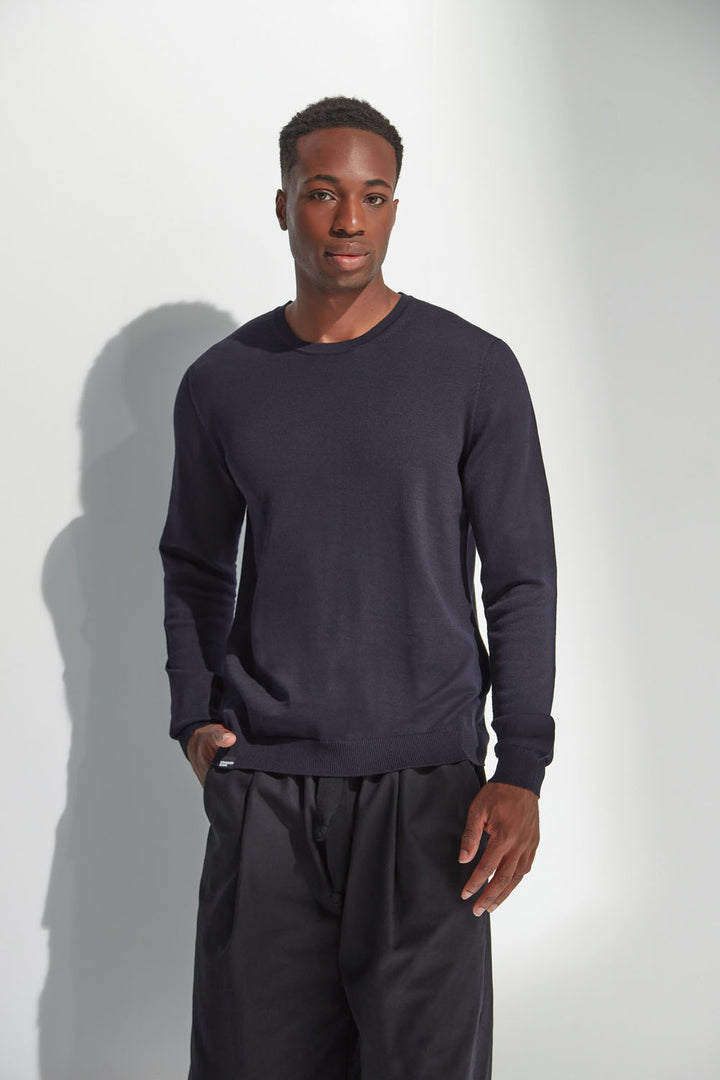Man wearing a dark navy long-sleeve shirt and black pants against a white background
