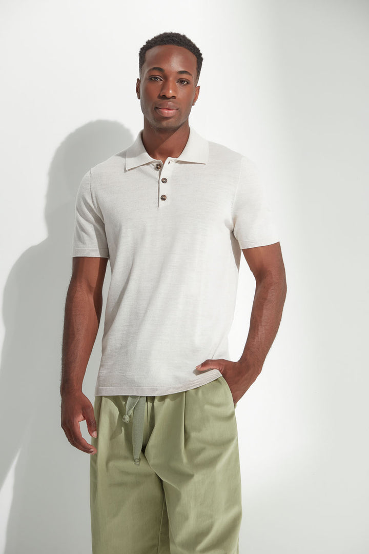 Man wearing a light-colored polo shirt and light green pants against a white background