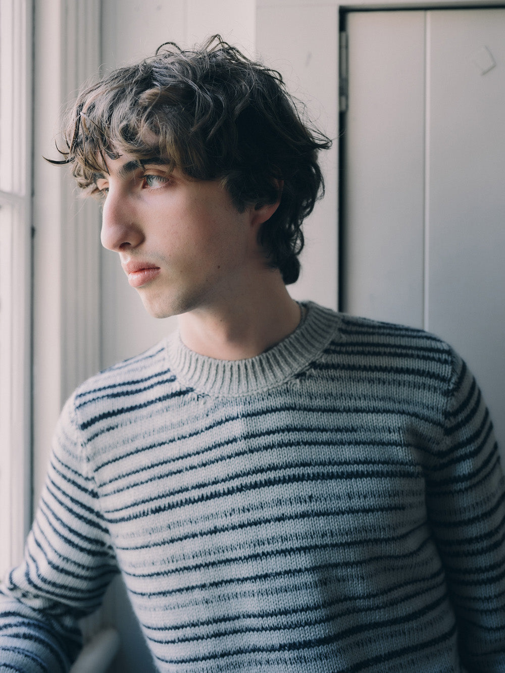 Man wearing a striped sweater standing against a neutral background