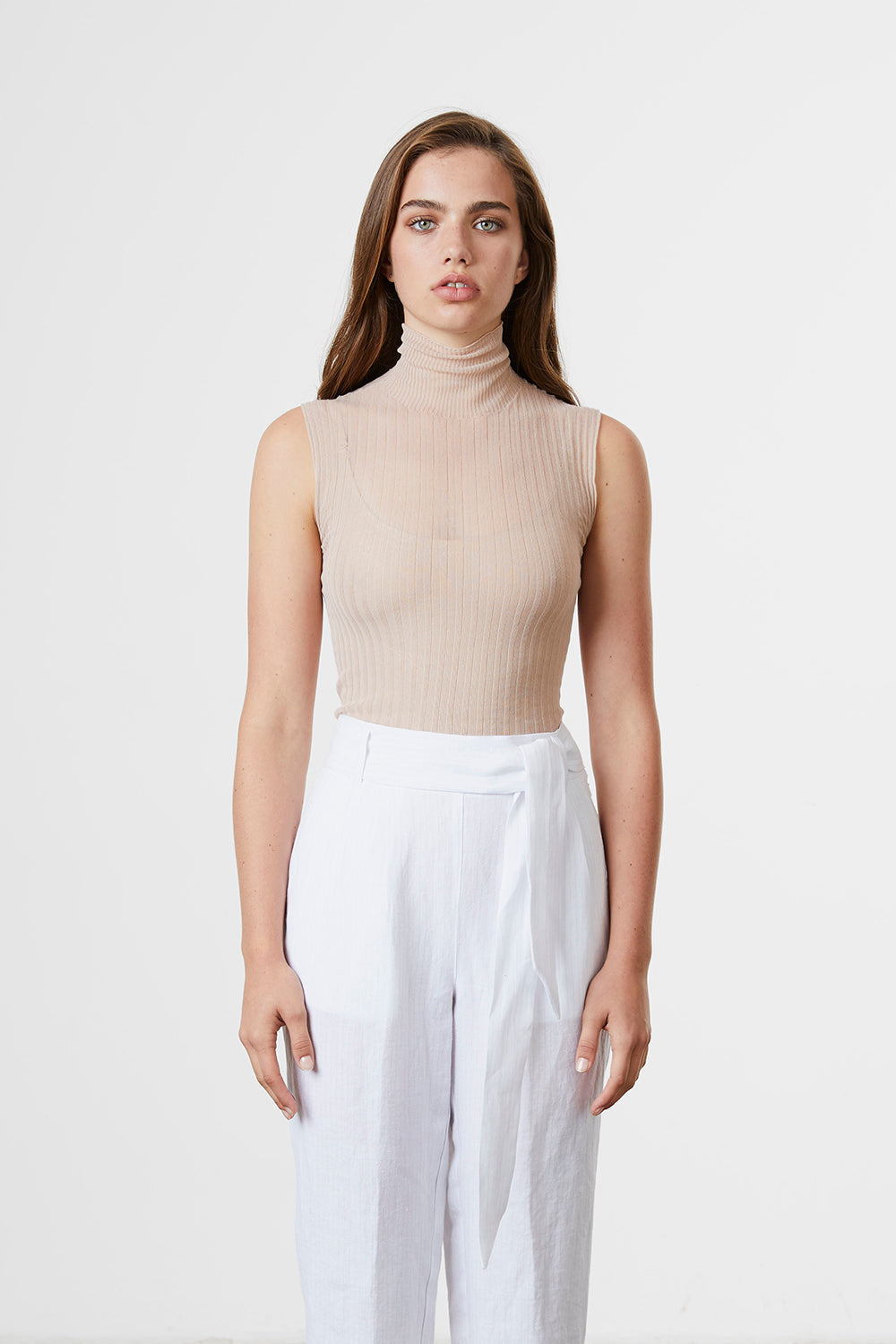 A woman standing wearing a blush-coloured Standard Issue Cotton Tulle High Neck skivvy.