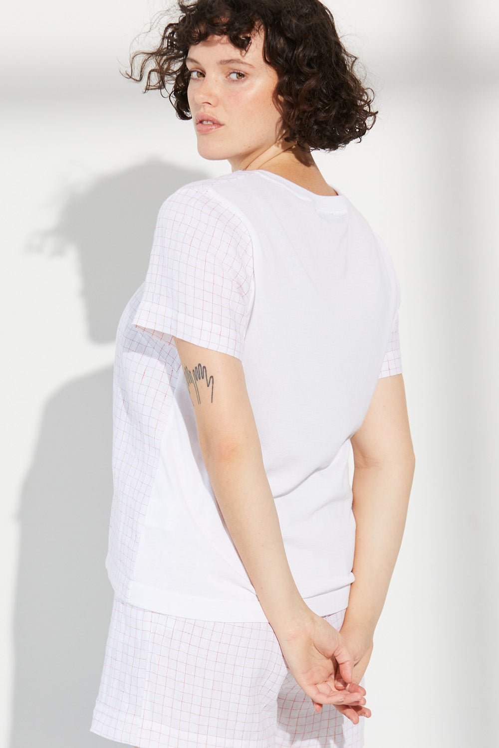 A woman looking over her shoulder wearing a white Standard Issue Grid Linen Tee.