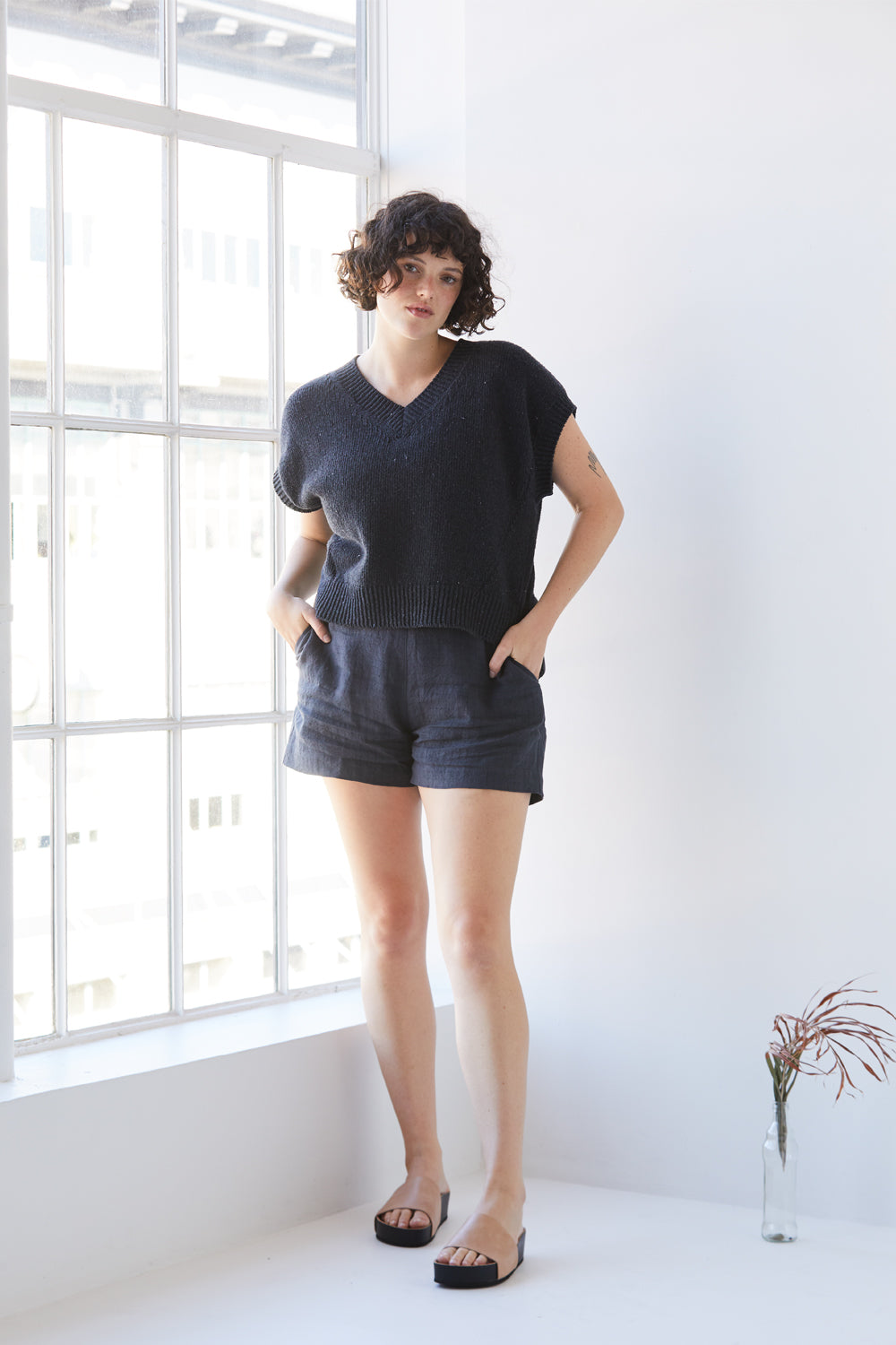 A woman standing wearing a charcoal-coloured Standard Issue Grid Linen Short.