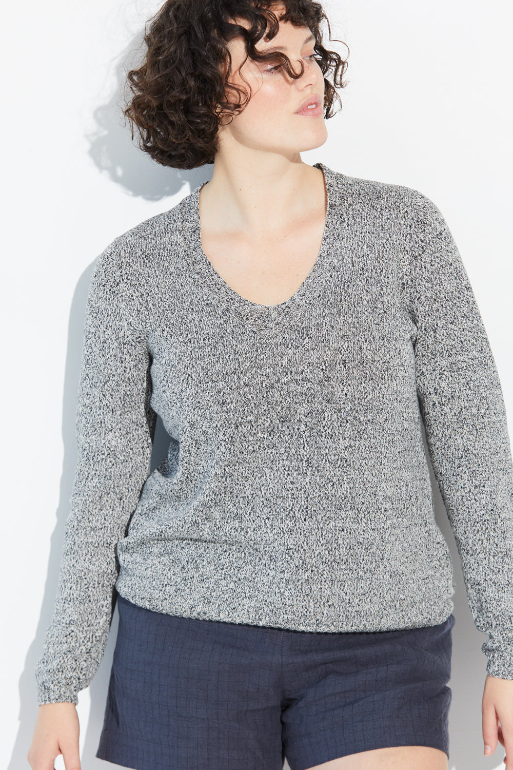 A woman looking sideways wearing a twist-coloured Standard Issue Linen V jumper.