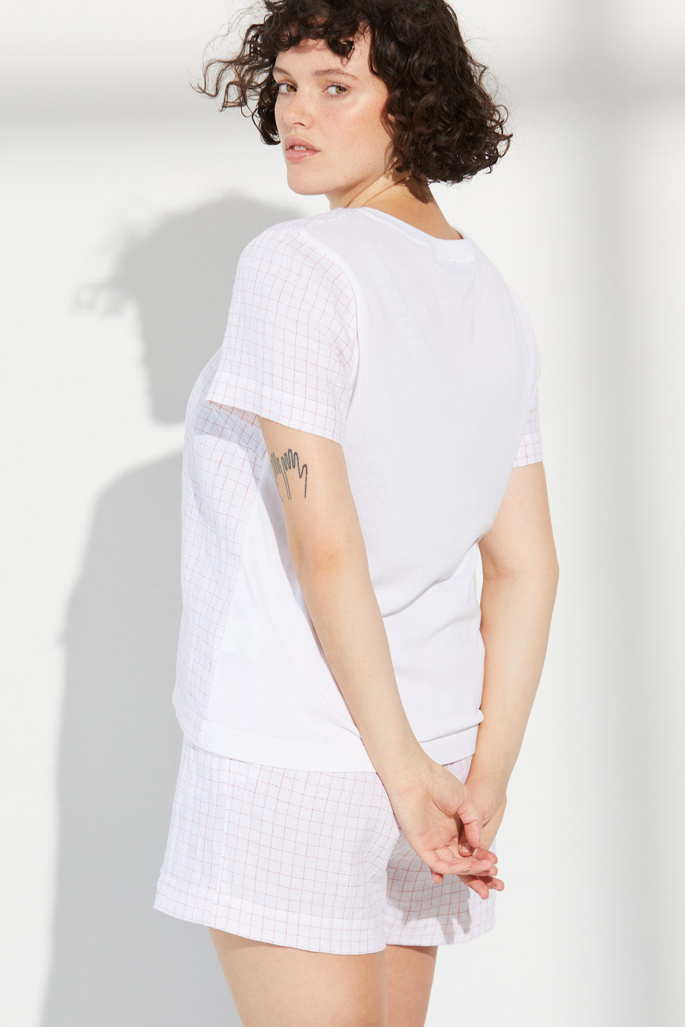 A woman standing wearing a white Standard Issue Grid Linen Short.